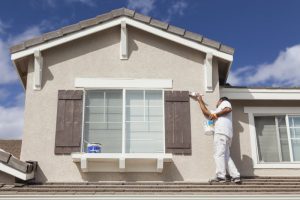 A man painting his home’s exterior.