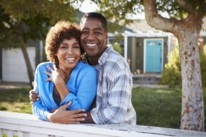 smiling couple in front of their house