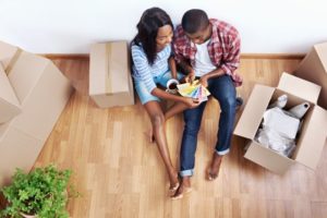 a couple sitting on the floor of their new home choosing paint together