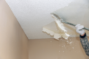 a person removing a popcorn ceiling inside a home